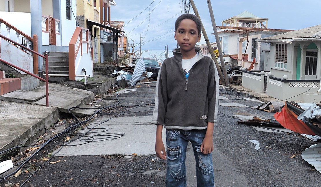 Young boy on a street in Puerto Rico damaged by hurricane Maria.