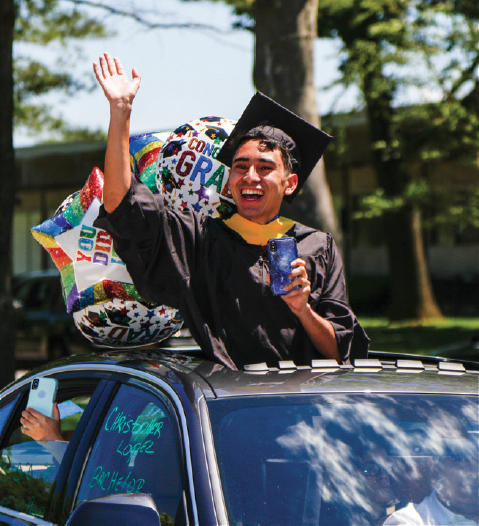 Student waving out of car sunroof during Car-mencement