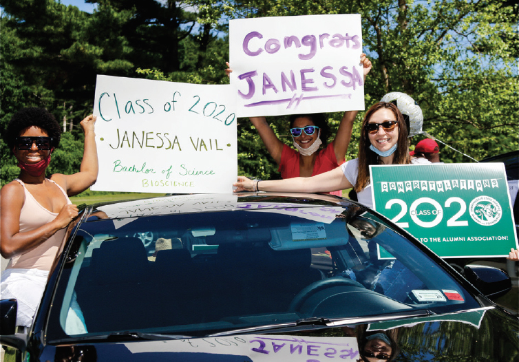 Three students holding handmade signs at Car-mencement