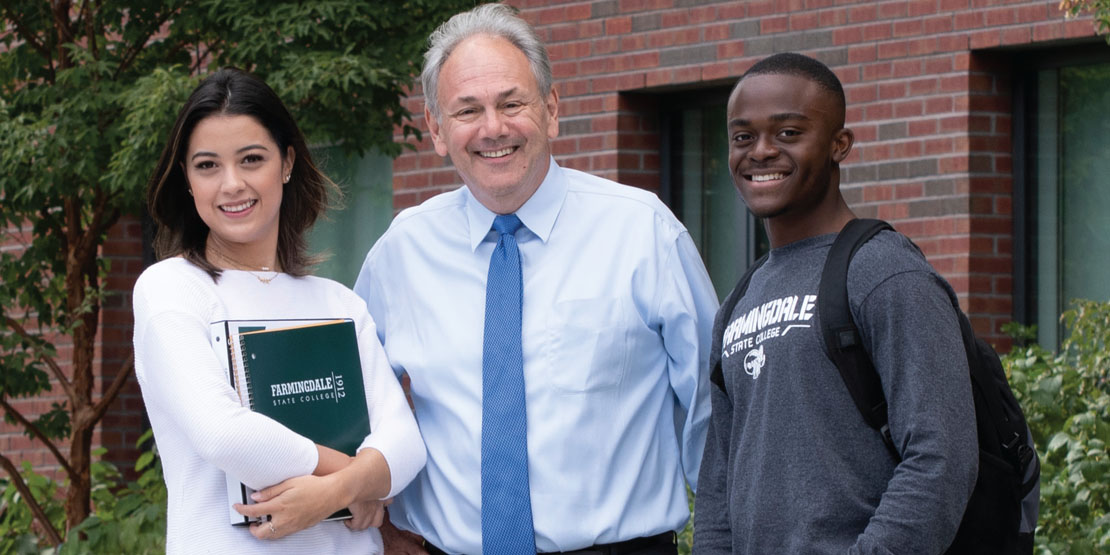 President John S. Nader standing with two students outside the Campus Center