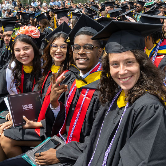 A row of students sitting and smiling at the spring 2022 commencement