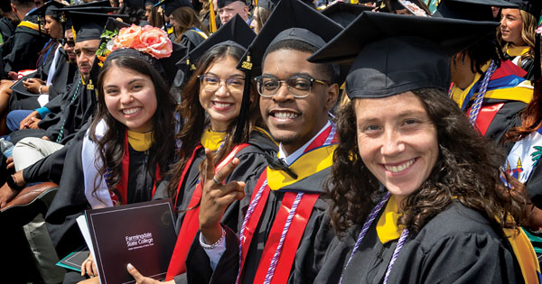 A row of students sitting and smiling at the spring 2022 commencement