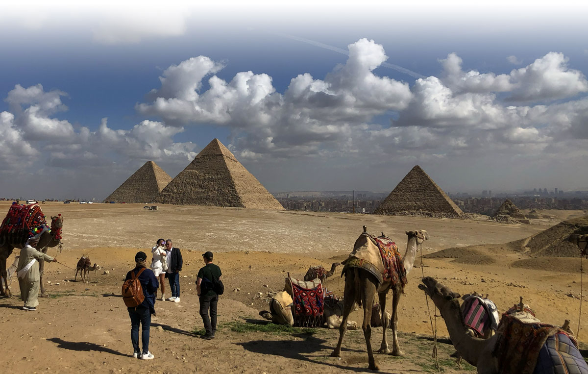 Students and camels with pyramids in the background