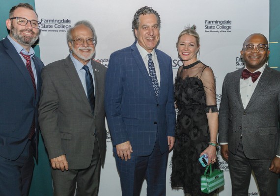 Group of people smiling at the camera in front of a Farmingdale State College branded backdrop